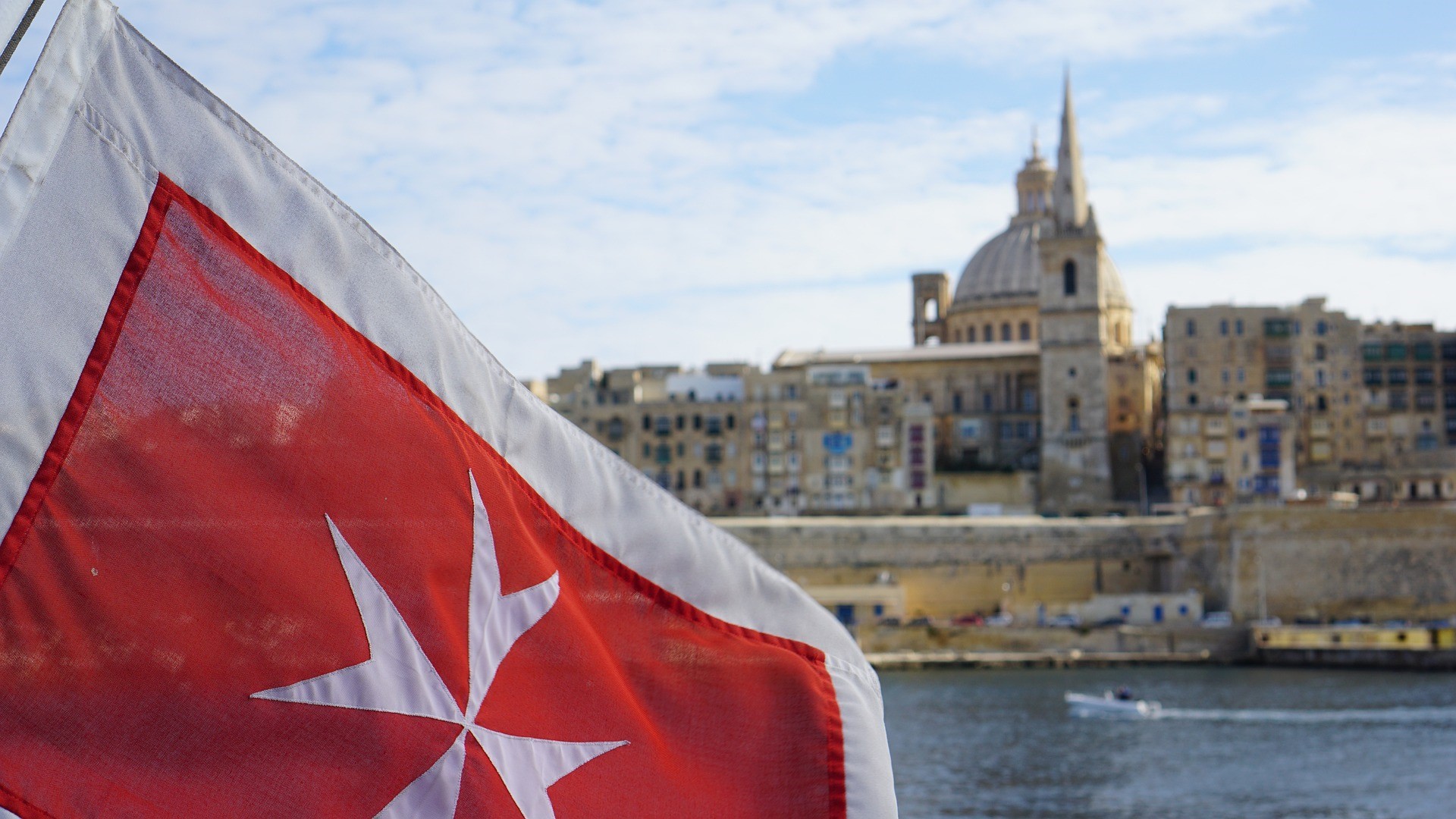Bandera de la cruz de Malta, con La Valeta de fondo.