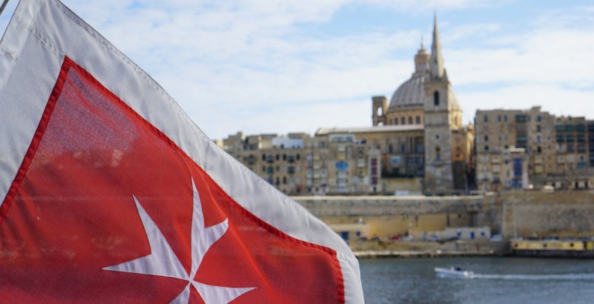 Bandera de la cruz de Malta, con La Valeta de fondo.